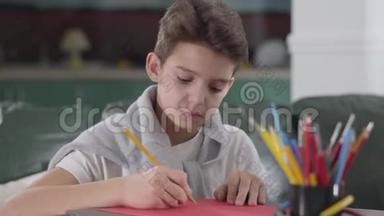 黑种人白人小学生坐在桌子旁学习的特写照片。 可爱的男孩在运动中写下